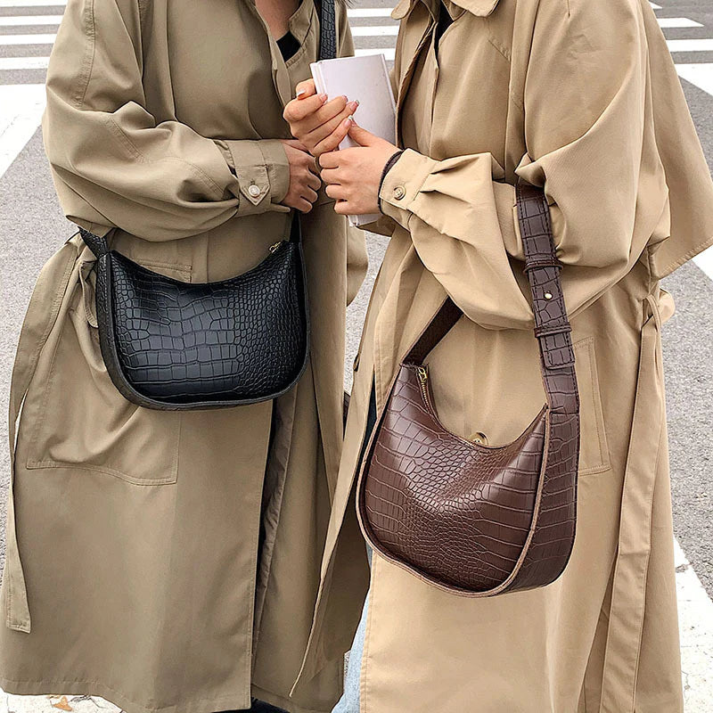 Women holding crocodile-patterned leather handbags